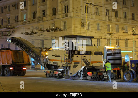 Lavoro su strada con un asfalto fresatrice stradale rimuovendo il vecchio marciapiede da una strada surfaceat notte Foto Stock