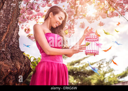 Bella donna - tenere le mani birdcage - circondato da un sacco di farfalle Foto Stock