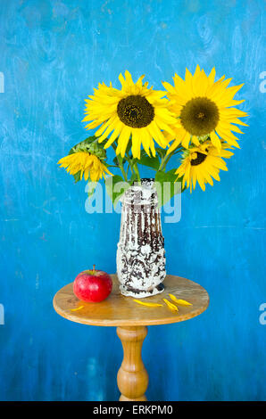 Vaso antico con belle distese di girasoli e mela rossa sul tavolo Foto Stock