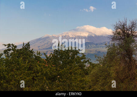 Il vulcano Etna fotografata da Taormina sotto un cielo blu ed una nube contro la montagna italiana con boschi e alberi in th Foto Stock