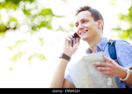 L'uomo azienda mappa all'aperto e parla al telefono Foto Stock