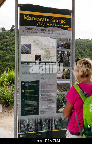 Donna walker la lettura della scheda di informazioni all'inizio dell'Manawatu Affitto Gorge a piedi, Nuova Zelanda. Foto Stock