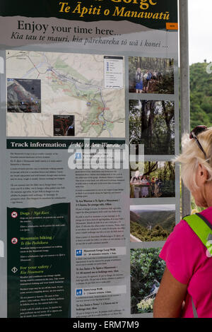 Donna walker la lettura della scheda di informazioni all'inizio dell'Manawatu Affitto Gorge a piedi, Nuova Zelanda. Foto Stock