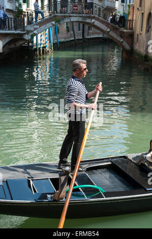 Venezia, Italia - 24 Aprile 2013: gondoliere veneziano sterline la sua gondola lungo le acque verdi di un canale. Foto Stock