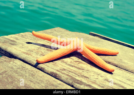 Una stella gialla su un vecchio molo in legno sul mare, con un effetto retrò Foto Stock