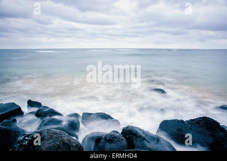 Surf lavaggio fino intorno a rocce; Wailua, Kauai, Hawaii, Stati Uniti d'America Foto Stock