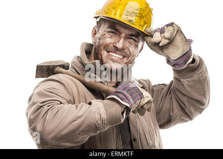 Giovane lavoratore sporco uomo con elmetto casco tenendo un martello e sorridente isolati su sfondo bianco Foto Stock