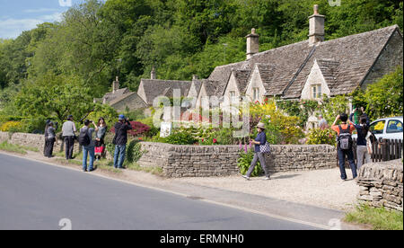 Turisti asiatici a fotografare il XVII secolo cottage in pietra a Bibury, Cotswolds, Gloucestershire, Inghilterra Foto Stock