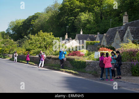 Turisti asiatici a fotografare il XVII secolo cottage in pietra a Bibury, Cotswolds, Gloucestershire, Inghilterra Foto Stock