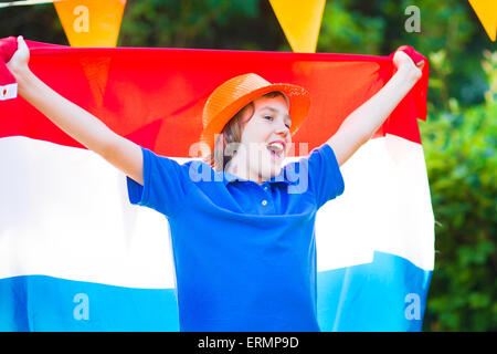 Ragazzo olandese, appassionato di calcio, il tifo e il supporto di squadra di calcio dei Paesi Bassi nel corso del campionato, celebrando la vittoria sportiva Foto Stock