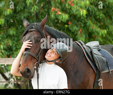 Allegro jockey giovane donna con cavallo di razza in esterno Foto Stock