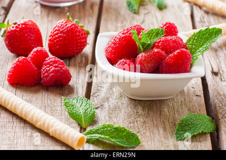 Freschi di lampone e fragola con foglie di menta sulla ciotola bianco Foto Stock