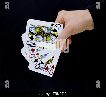 Croupier giocatore tenendo a portata di mano carta regine di picche quattro di un tipo su sfondo nero Foto Stock