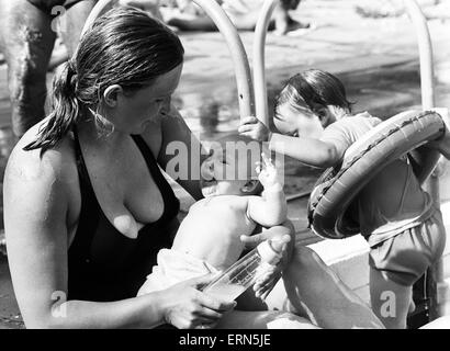 La madre e il bambino tenta di conservare al fresco a Birmingham lido durante la canicola estiva del 1976. Il 28 giugno 1976. Foto Stock