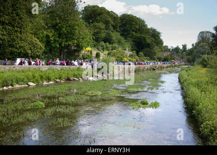 Scuola di francese i bambini a piedi lungo il Fiume Coln a Bibury, Cotswolds, Gloucestershire, Inghilterra Foto Stock