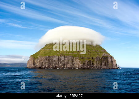 Remota isola roccioso coperto da un cappuccio di nuvole Foto Stock