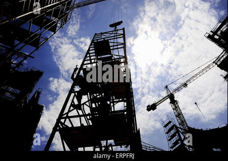Ripresa industriale con il lavoratore edile stagliano contro il cielo blu lavorando su una impalcatura Foto Stock