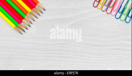 Luminose matite colorate e graffette su legno bianco angoli del desktop. Elevato angolo di visualizzazione in formato orizzontale. Foto Stock