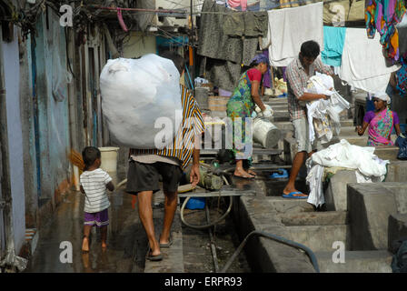 Gli uomini vestiti di lavaggio a Mahalaxmi Dhobi Ghat aperto lavanderia a gettoni, Mumbai, Maharashtra, India. Foto Stock