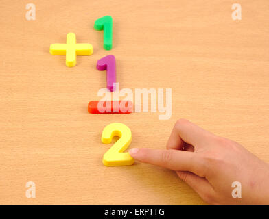 Bambino facendo una somma con elementi in plastica sulla scuola scrivania di legno Foto Stock