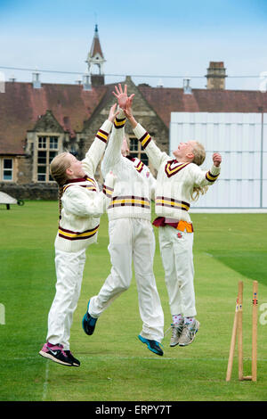 Junior ragazze celebrare tenendo un paletto durante una partita di cricket nel Wiltshire, Inghilterra Foto Stock