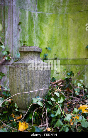 Vecchia urna di pietra di fronte a una parete Foto Stock