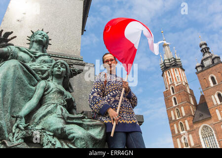 Giovane donna con la bandiera della Repubblica di Polonia sulla piazza principale di Cracovia, la chiesa di Santa Maria in background. Foto Stock