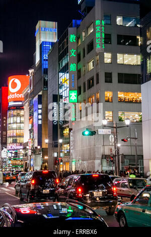 Il Ginza di notte. Guarda lungo la strada piena di traffico con il Mikimoto Store dentro e dietro l'edificio Sanai all'incrocio di Ginza. Foto Stock