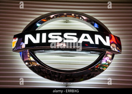 Nissen auto marca logo segno sulla facciata bianca foderata in Ginza, Tokyo. Scatto notturno, con luci dai colori brillanti riflesse in metallo argentato. Foto Stock