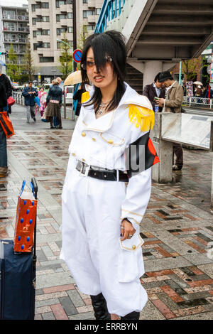 Giovani donne giapponesi vestite in uniforme di stile militare bianco con fascia da braccio nera, che si posa in strada ad Harajuku, Tokyo. Contatto visivo. Foto Stock