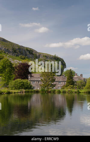 La luce del sole estivo & pittoreschi cottage in pietra stand sulle rive di un suggestivo lago di pesca, Kilnsey Crag oltre - Kilnsey Park, Yorkshire Dales, Inghilterra, Regno Unito. Foto Stock