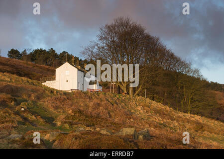 Nel sole sotto un cielo blu, solitaria e isolata, pozzetti bianchi Spa Cottage, è arroccato su un pendio - Ilkley Moor, West Yorkshire, Inghilterra, Regno Unito. Foto Stock