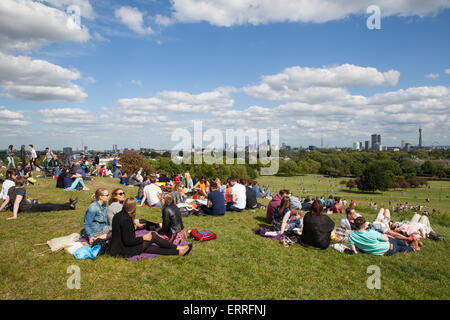 Turisti ed escursionisti rilassarsi al sole su Primrose Hill a Londra Foto Stock