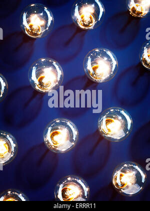 Un gruppo di accese le lampadine a incandescenza brillante su sfondo blu Foto Stock