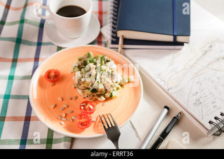 Insalata russa per la colazione su un panno a scacchi e taccuini Foto Stock