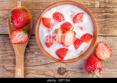 La fragola e yogurt in una ciotola di legno su sfondo di legno Foto Stock