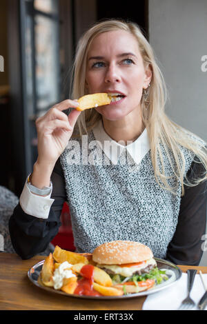 Donna bionda ubicazione nel ristorante con un burger Foto Stock