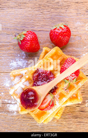 Waffles fatti in casa con confettura di fragole su sfondo di legno Foto Stock