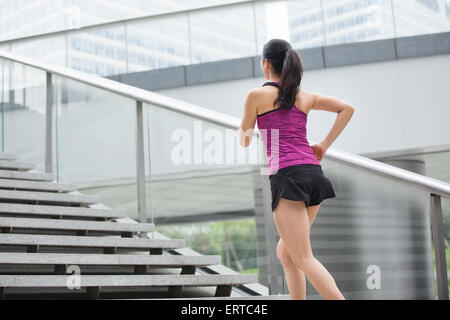 Giovane donna in esecuzione su per le scale per esercizio Foto Stock