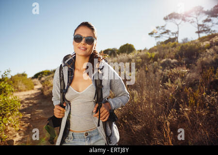 Ritratto di una giovane e bella donna escursionista trekking in natura. Giovane donna caucasica indossando occhiali da sole guardando la fotocamera con un Foto Stock