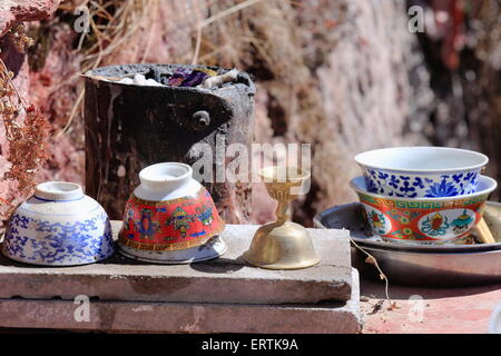 Set di tazze di ceramica-ciotole decorati con ashtamangala-buddista simboli di buon auspicio a candelabro in ottone-secchio di vernice forno. Il Tibet. Foto Stock