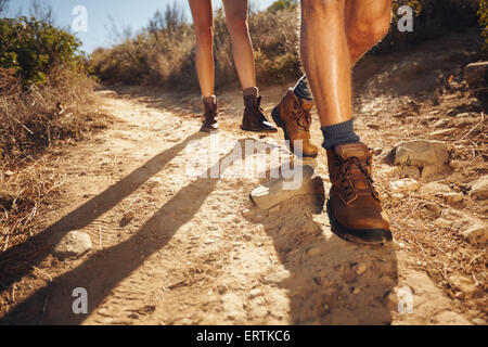 Close-up di gambe di giovani escursionisti a piedi sul percorso del paese. Coppia giovane trail veglia. Focus su scarpe da escursionismo. Foto Stock