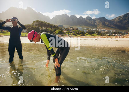 Gli atleti riposo dopo il triathlon la sessione di formazione. Giovane uomo e donna in piedi in acqua facendo una pausa dalla pratica. Foto Stock