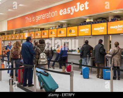 La Easy Jet compagnia aerea bilancio banco di check-in presso l'aeroporto di Gatwick di Londra, Inghilterra, Regno Unito - con una linea di persone in coda Foto Stock