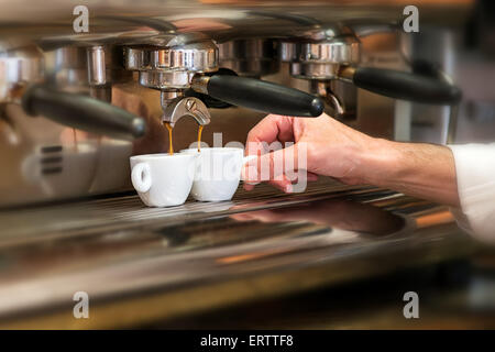 Vista ravvicinata della mano di un uomo che lavora in una casa di caffè la preparazione di caffè espresso Foto Stock