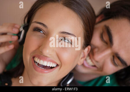 Giovane con le cuffie, uomo whispering in womans orecchio Foto Stock