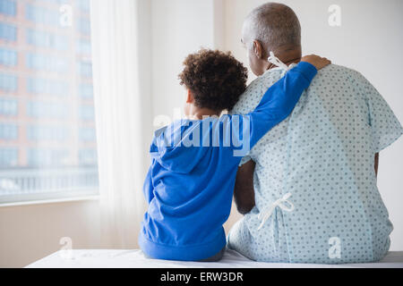 Razza mista nonno seduto con il nipote in ospedale Foto Stock