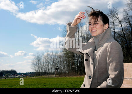 Giovane donna seduta su una panchina in esterno e in natura Foto Stock