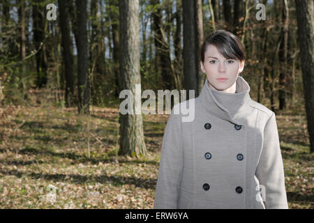 Giovane donna in costa in piedi in una foresta Foto Stock