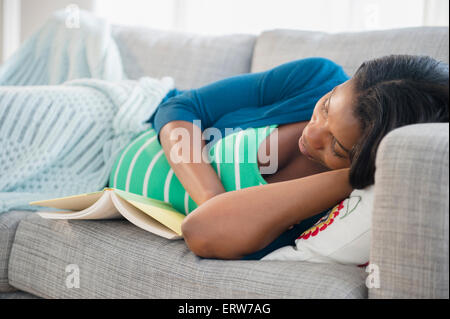 Nero donna incinta a sonnecchiare sul divano Foto Stock